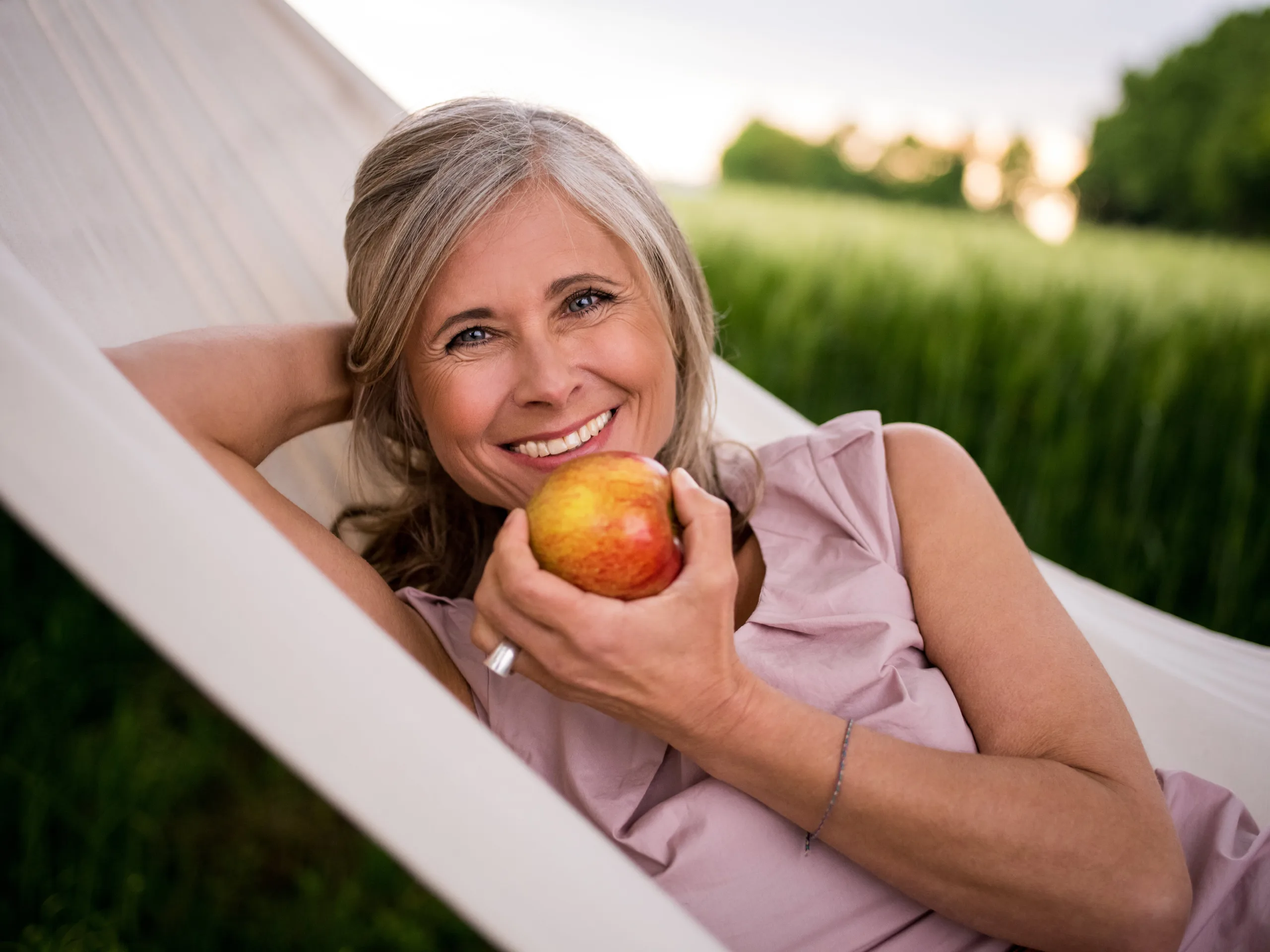 mujer comiendo manzana y sonriendo por no tener estreñimiento